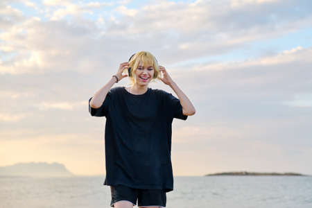 Female hipster teenager in headphones enjoying music on the beachの写真素材