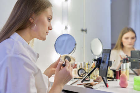 Young woman recording video, makeup beauty blog using smartphone.の写真素材