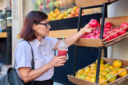 Woman in outdoor fruit juice bar with fresh juiceの写真素材
