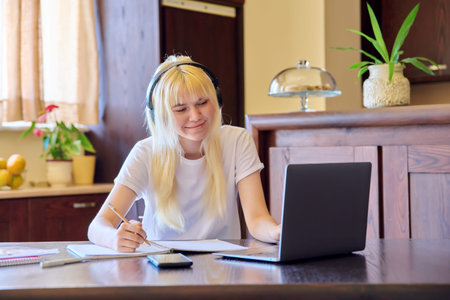 Teenage female student studying at home using a laptop.