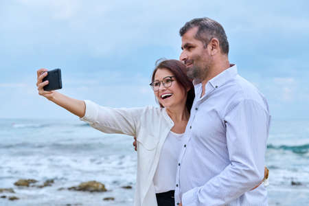 Happy mature couple taking selfie photo on smartphone.の写真素材