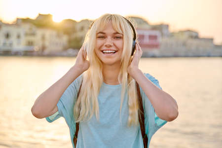 Outdoor portrait of happy young blonde woman wearing headphonesの写真素材