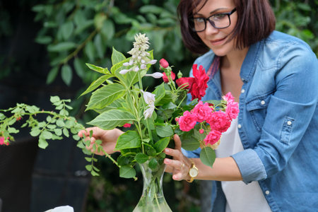 Woman making bouquet of flowers in vase outdoor