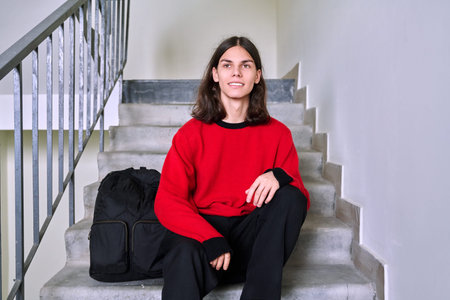 Portrait of a handsome teenage male 17, 18 years old sitting on the stairs