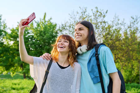 Young couple, laughing teenagers taking selfie photo on smartphoneの写真素材