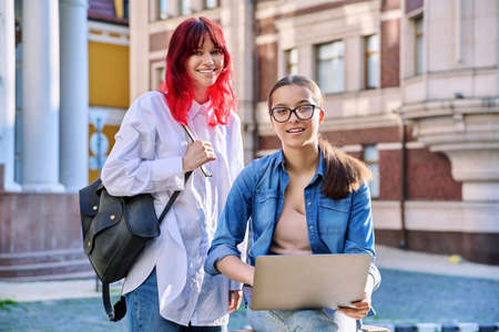 Two teenage female students using outdoor laptop, city street backgroundの写真素材