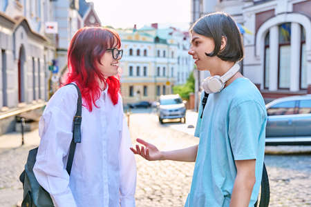 Teenage friends male and female talking on the street of cityの写真素材