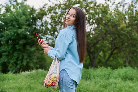 Pretty teenage girl in the park using smartphone
