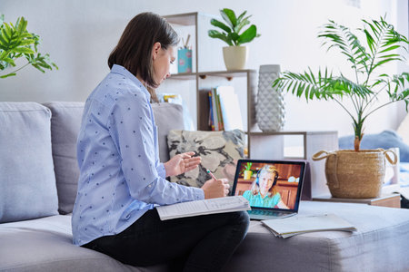 Young female teacher making video conference for child girl sitting in home