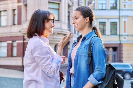 Talking mom and teenage daughter outdoors, on city streetの写真素材