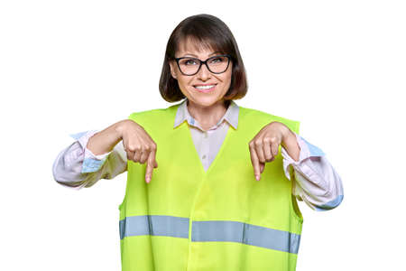 Industrial woman in safety vest on white isolated background pointing down, copyspaceの写真素材