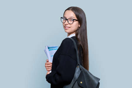Teenage female student with backpack notebooks on color backgroundの写真素材