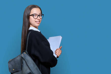 Teenage female student with backpack notebooks on color backgroundの写真素材