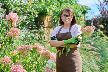 Portrait of gardener woman with pruner looking at camera in garden