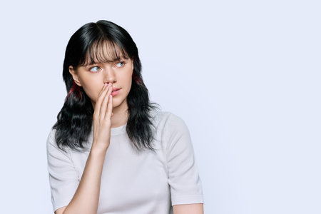 Young teenage woman whispering a secret, over white background