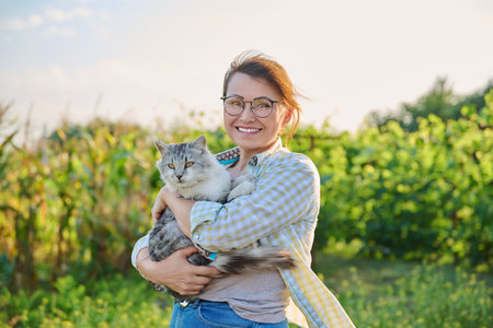 Outdoor portrait of middle aged woman with cat in her armsの写真素材