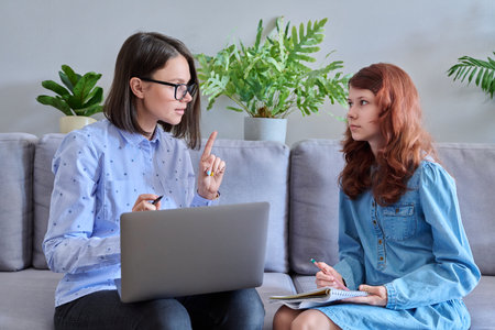 Preteen girl studying together with teacher, in office on couchの写真素材