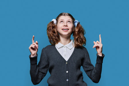Preteen girl showing hands up, space for text, blue backgroundの写真素材