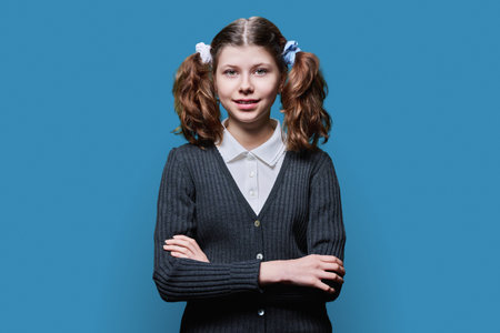 Portrait of smiling child schoolgirl on blue studio backgroundの写真素材