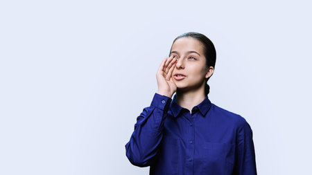 Teenage girl talking to the side, copy space, white studio background
