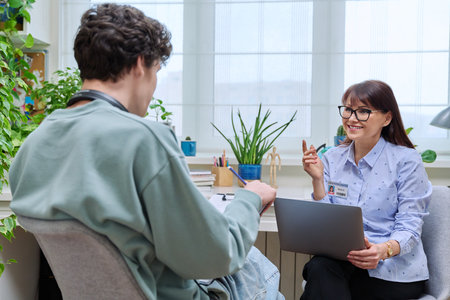 Female education center worker talking to young male college studentの写真素材
