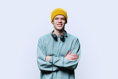 Young male in yellow cap sweatshirt with headphones on white backgroundの写真素材