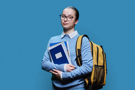 Portrait of teen girl high school student on blue studio backgroundの写真素材