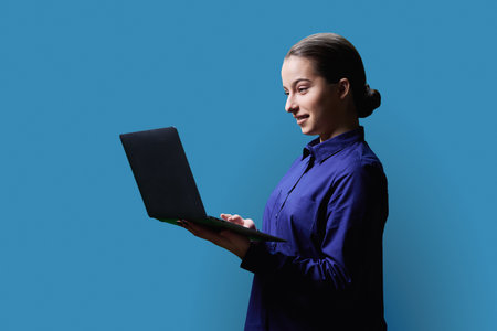 Teenage girl high school student using laptop on blue backgroundの写真素材