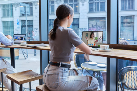 Virtual video chat of teenage girls friends, using laptop in cafeの写真素材