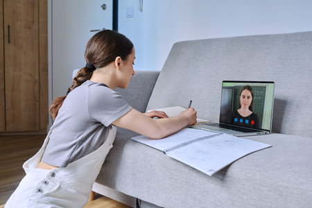 Teenage girl studying looking at laptop with online lesson