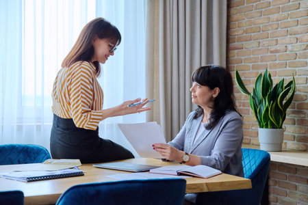 Two mature business women working in office, with papers, laptopの写真素材