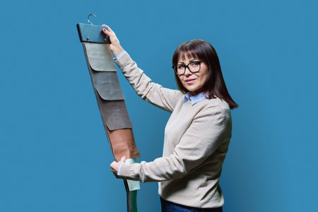 Woman with samples of fabrics for curtains and upholstery on blue backgroundの写真素材