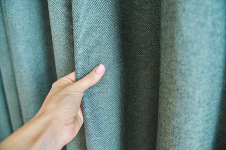 Womans hand touching curtain, green fabric with burlap texture, blackout fabricの写真素材