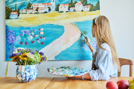 Young woman artist painting picture on canvas on wallの写真素材