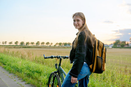 Teenage female with backpack on bike looking at cameraの写真素材