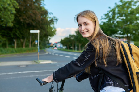 Portrait of teenage student girl with backpack on bicycleの写真素材