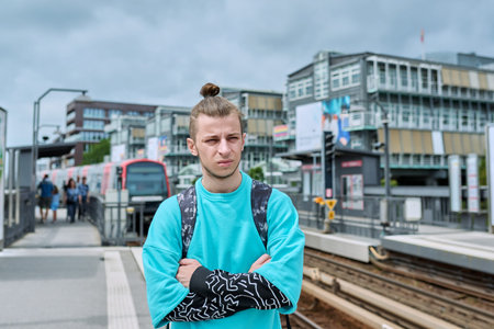Portrait of young confident guy at railway station of electric city train