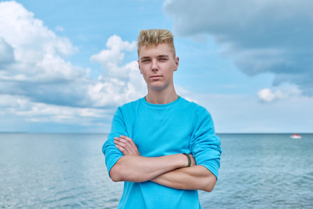 Portrait of serious confident young guy outdoor, on sea beach