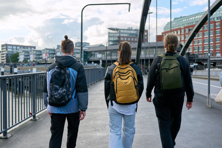 Rear view of three students with backpacks walking togetherの写真素材