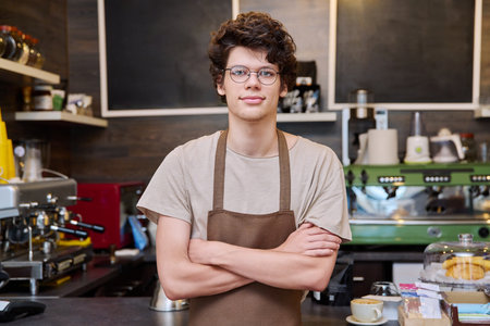 Young confident male coffee shop worker with crossed armsの写真素材