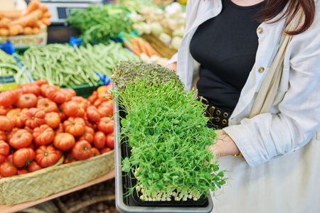 Close-up of trays with various microgreens in hands of woman at farmers market