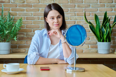 Young happy brunette looking at her face in mirrorの写真素材