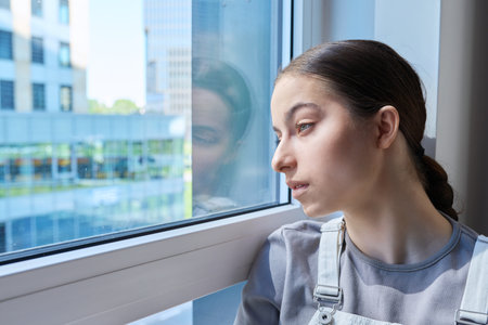 Sad stressed teenage girl looking out the window,の写真素材