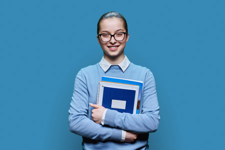 Portrait of teenager girl high school student on blue backgroundの写真素材