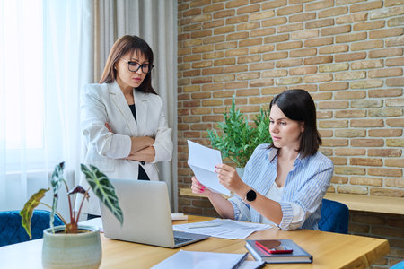 Two serious business women talking working in modern officeの写真素材