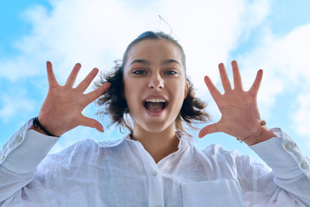 Close up face of emotional laughing female teenager looking down at camera