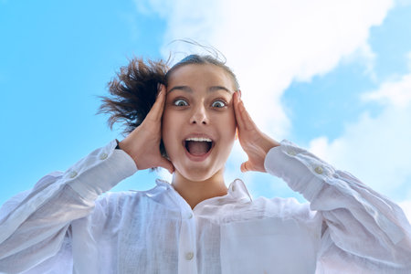 Close up face of emotional laughing female teenager looking down at cameraの写真素材