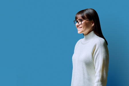 Profile view of middle aged happy woman, blue background, copy spaceの写真素材