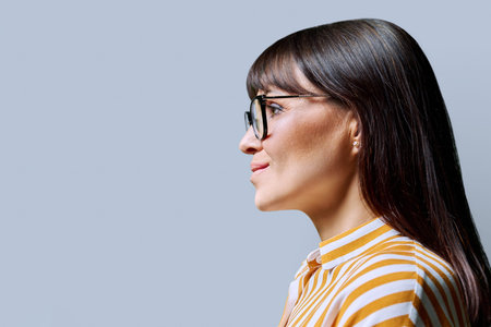 Profile view of middle aged smiling woman, gray background, copy space