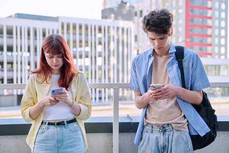 Teenage friends guy and girl using smartphones, urban outdoorの写真素材
